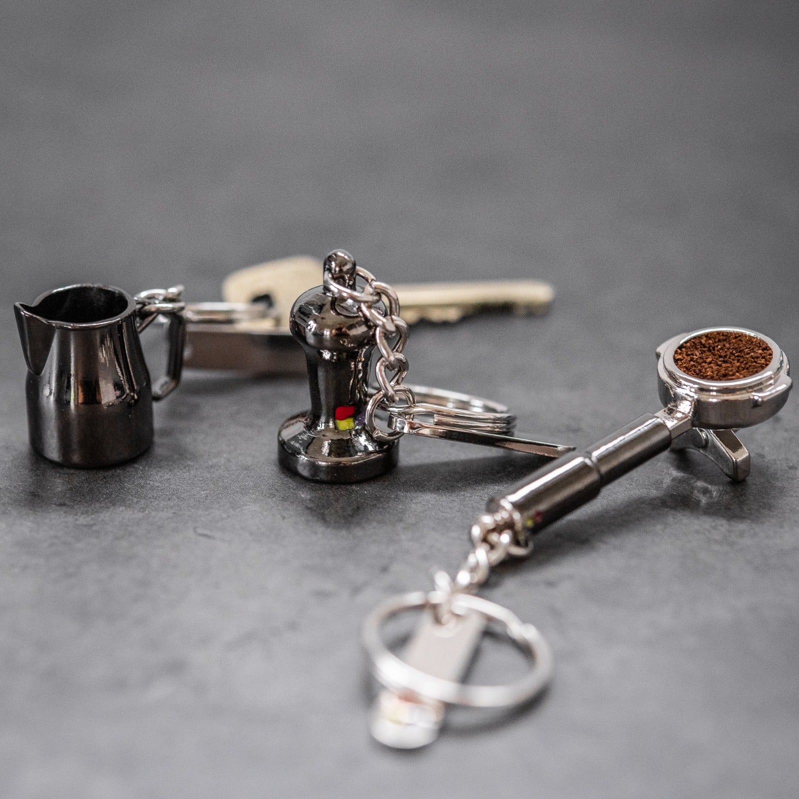 A set of keys and a small metal keychain cup on a dark surface.